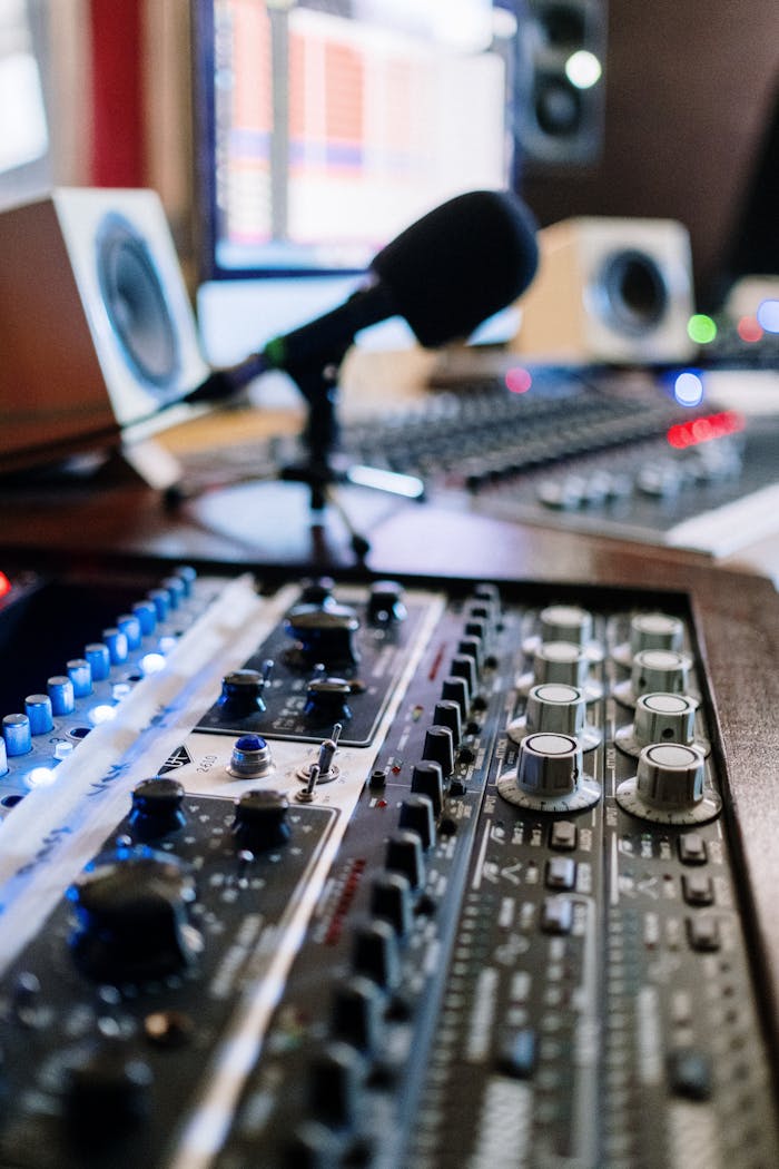 Close-up of audio mixing console with microphone and monitors in a studio setting.